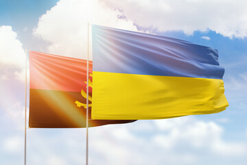 Sunny blue sky and flags of ukraine and angola
