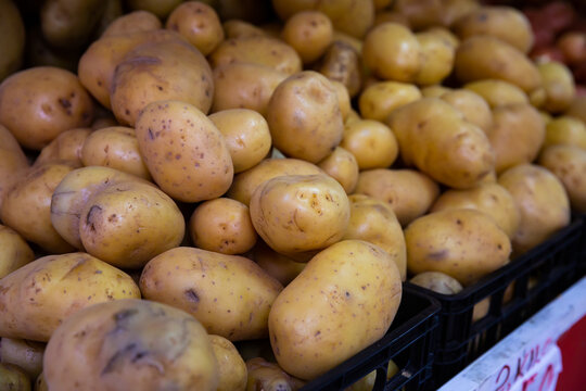 Pile of ripe potatoes in plastic box on showcase of greengrocery..