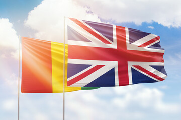 Sunny blue sky and flags of united kingdom and guinea