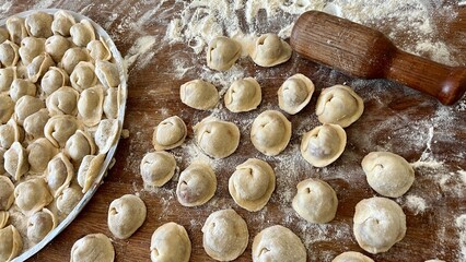 grandmother for 80 years with love prepares dumplings she is the guardian of the family, she wears a white scarf and a blue jacket, she sits in the kitchen and sculpts dumplings and dumplings shakes