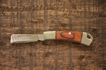 Small metal and wooden razor on a brown background. 
