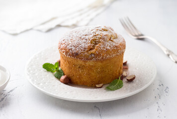 Freshly baked sweet homemade carrot semolina pie or mannik with nuts sprinkled with powdered sugar on a light blue background