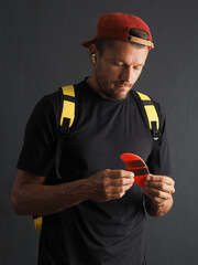 Man surfer  holding orange color surf fin in hands, thinking about surfing.