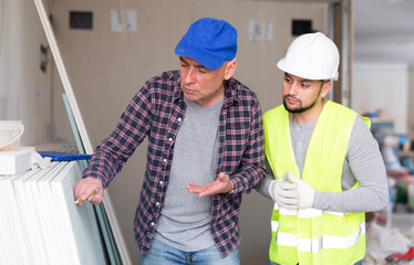 Focused creative adult male interior designer giving instructions to construction team foreman and...