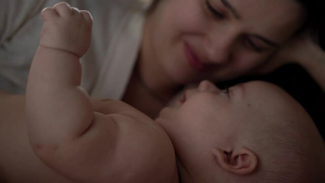 Newborn Baby With Young Mom look Into Each Other Eye. Cute Smiling Teethless Kid Face Portrait. Woman Kissing With Child Look At Camera. Infant, Mother Day, Childbirth, Beginning, Relationship Concept