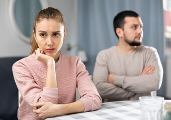 Offended frustrated young woman sitting at table at home after spat with her boyfriend. Couple relationship problems concept..