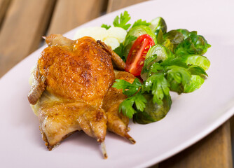 Fried quail-tobacco served with tasty vegetables and greens at plate