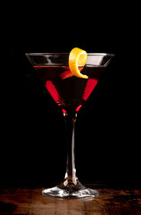 front view martini glass with orange slice and cherry drink on dark background on wooden table