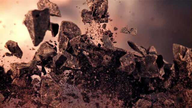 Pieces of chocolate go up and down. On an orange background. Filmed on a high-speed camera at 1000 fps.