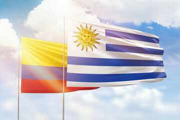 Sunny blue sky and flags of uruguay and colombia