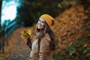 smiling young female in brown coat and yellow hat