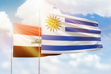 Sunny blue sky and flags of uruguay and iraq
