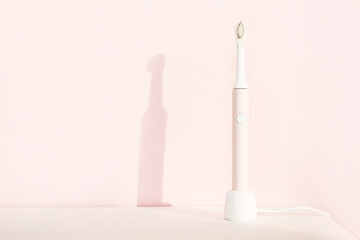 New modern ultrasonic toothbrush. Jaw model and dental care supplies on pink pastel background. Oral hygiene, dental and gum health, healthy teeth. Dental products Ultrasonic vibration toothbrush.