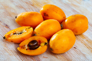 Closeup of whole and halved organic yellow loquat fruits on wooden background