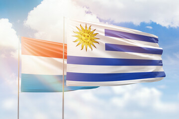 Sunny blue sky and flags of uruguay and luxembourg