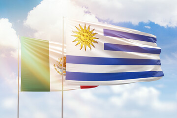 Sunny blue sky and flags of uruguay and mexico