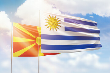 Sunny blue sky and flags of uruguay and north macedonia