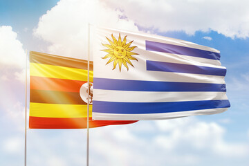 Fototapeta premium Sunny blue sky and flags of uruguay and uganda