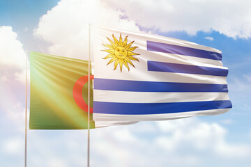 Sunny blue sky and flags of uruguay and algeria