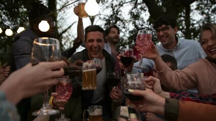 Multiracial People holding glasses of wine and beer making a toast – multi ethnic friends clinking glasses of wine and beer – cheerful friends clinking glasses above dinner table