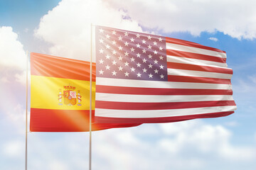 Sunny blue sky and flags of united states of america and spain