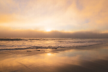Fototapeta na wymiar Dramatic sunset on the beach with marine layer clouds moving in from the ocean