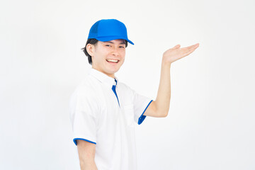 右側を手のひらで指すキャップとポロシャツのユニフォームの男性