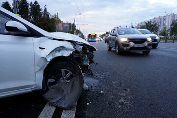  A broken car is standing on the road on which other cars are driving. The concept of careless driving a car.