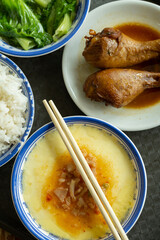 top view fast food of two chicken thighs and steamed eggs and vegetable and bowl of rice vertical composition