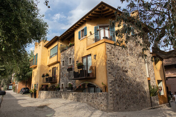old yollow and stone house in a cobbled street with beautiful balconies in a medieval italian tuscany villa in Val'Quirico, Tlaxcala, Puebla, Mexico