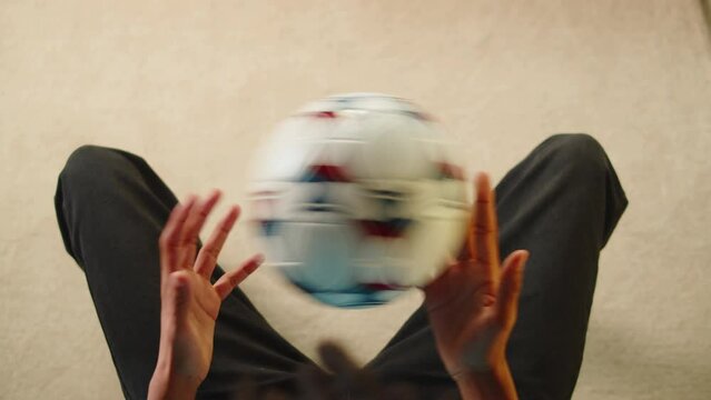 African American teenager fan holding soccer ball top view. Young man football player cheering favourite team at home, watching championship.