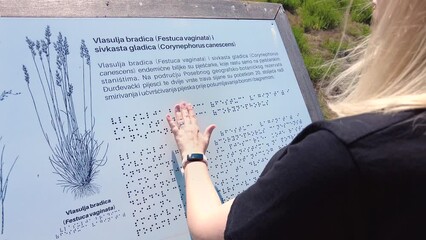 Blind girl is reading plant information written in The Braille Alphabet for Visually Impaired people