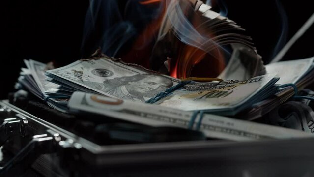 Burning American hundred dollar banknotes, Flame of fire from money. Rich person having stacks of 100 US dollars in metallic suitcase. Paper money loss, financial crisis and depressed economy. 