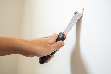 Man repairing crack white wall with spatula
