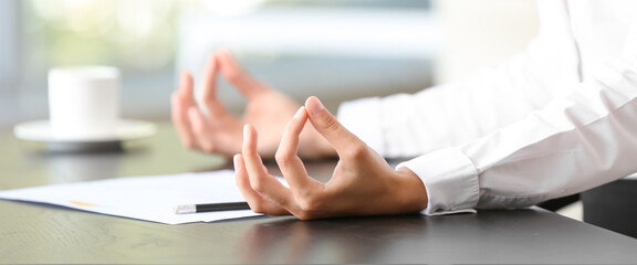 Young businesswoman meditating at workplace in office, closeup. Zen concept