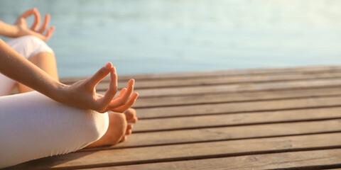 Beautiful young woman practicing yoga near river, closeup. Zen concept