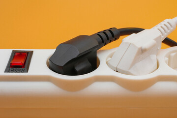 Black and white electric plugs plugged in power strip sockets with power switcher