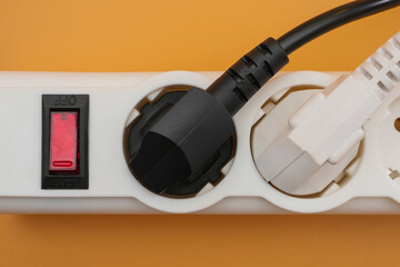 Top view on black and white electric plugs plugged in power strip sockets with power switcher