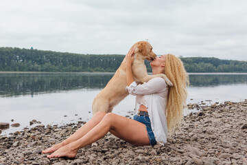 Young woman sitting with her labrador retriever dog on the river shore