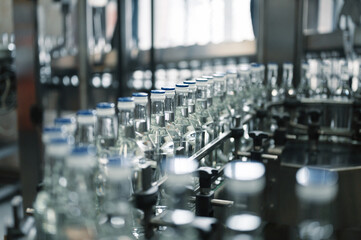 Closed glass bottles of upscale vodka transported by line