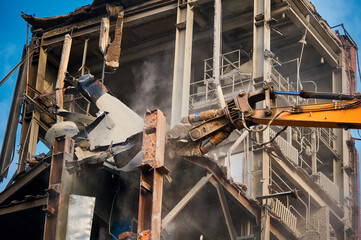 Fototapeta na wymiar Hydraulic cutter of crane demolishes old industrial building