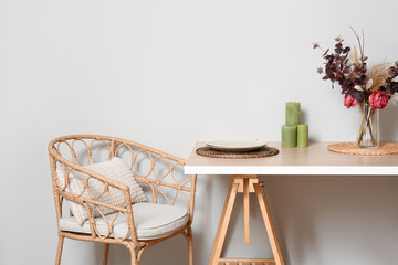 Comfortable armchair and served dining table near light wall