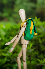 Hiker wooden doll  with backpack walking in the nature