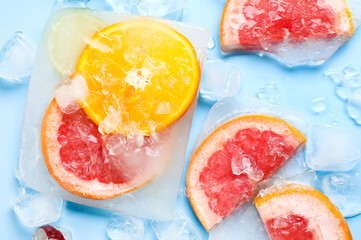 Fototapeta na wymiar Fresh slices of citrus fruits frozen in ice on blue background