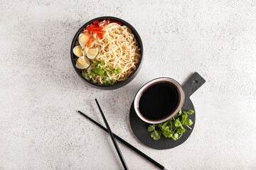 Bowl of tasty noodles with eggs and sauce on light background