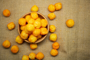 Cheese flavoured Puffs or balls closeup over gunny sack background