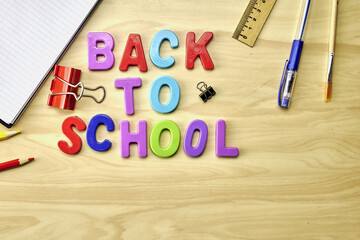 the phrase back to school is laid out in multicolored letters on the table a fountain pen a paint brush a ruler next to the concept of education school