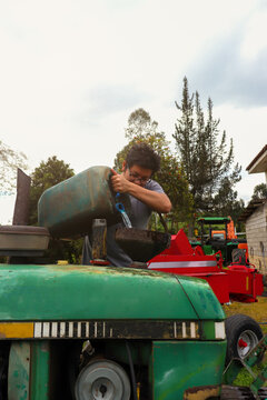 LLenando con diesen un tractor y de fondo maquinaria agricola hombre joven latino