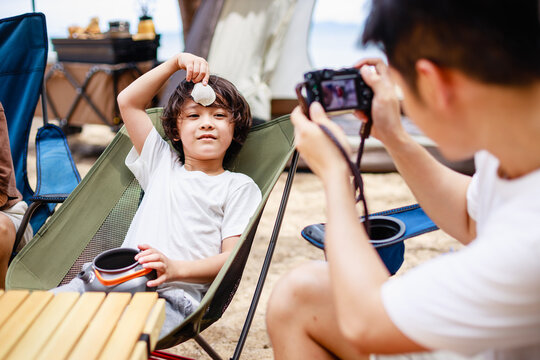 Father takes a picture of his son during picnic and camping on tropical beach. Summer activity. relax and outdoor activity lifestyle family concept. Father's day concept.