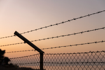 Barbed Wire Fence over Sky and Sea at Sunset Warm Colors